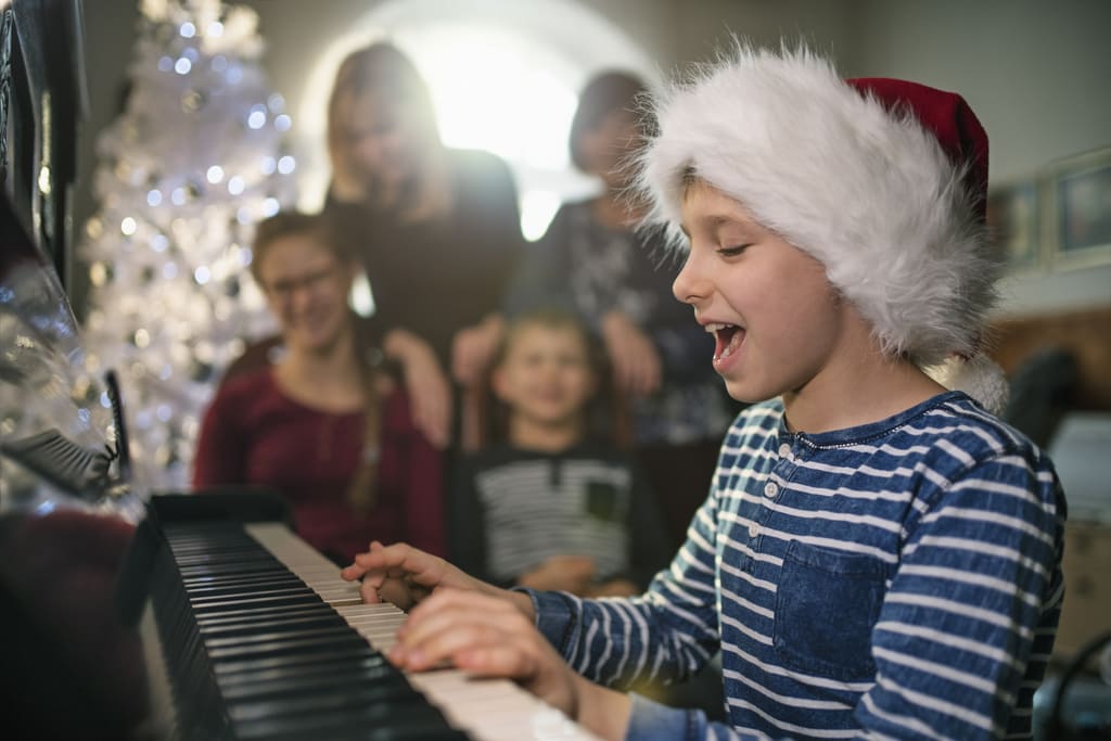 Bambino che suona il pianoforte per le feste di Natale